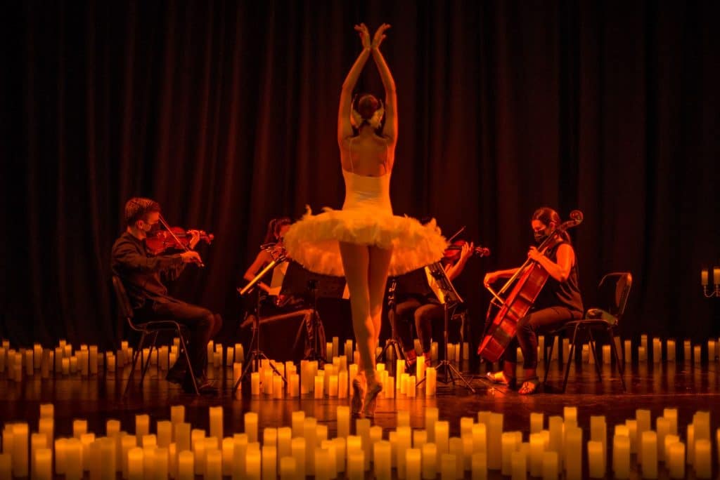 ballerina surrounded by candles and performing in front of a string quartet
