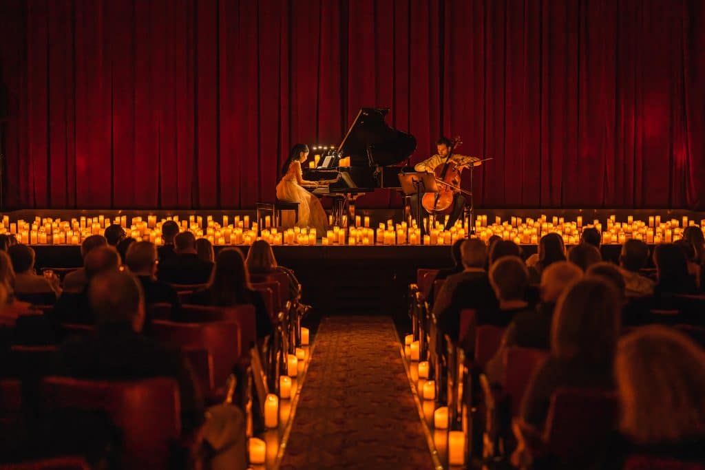 pianist and cellist performing on stage surrounded by candles