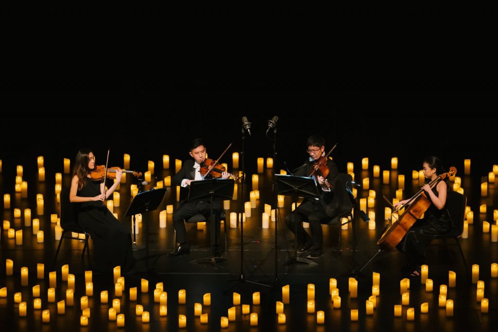 string quartet on stage surrounded by hundreds of candles
