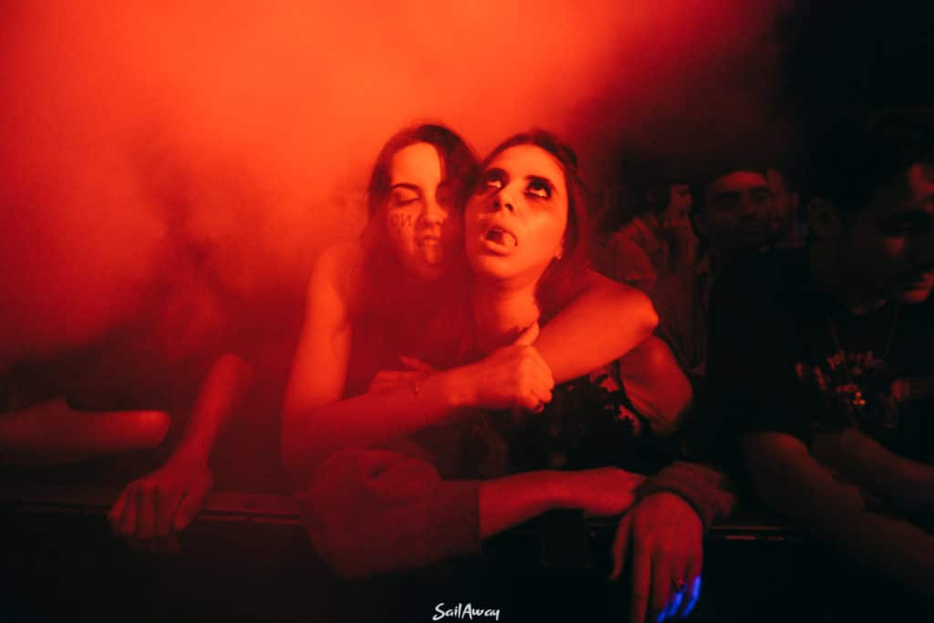 one woman hugging another woman from behind, both pulling halloween faces at dance party