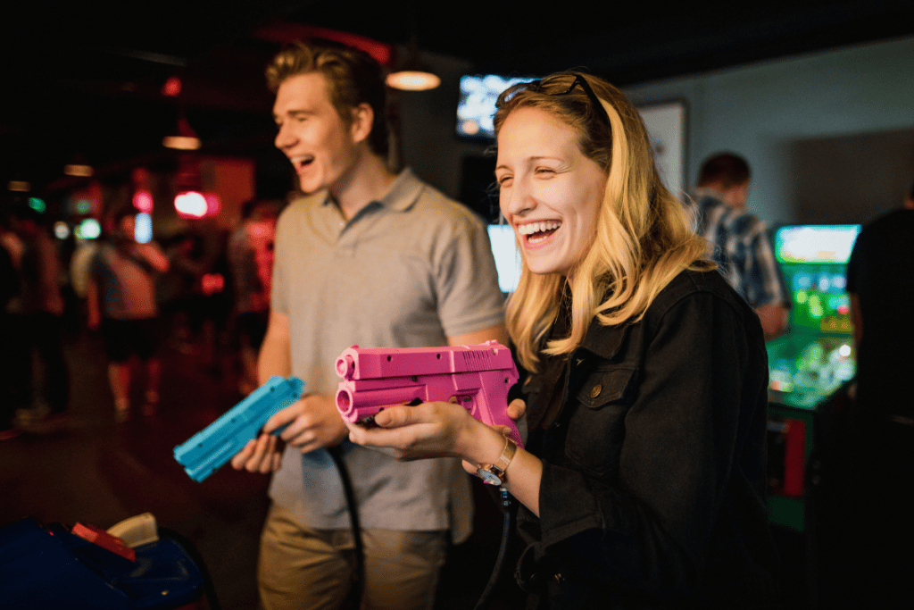 A man and a woman having fun while playing an arcade game