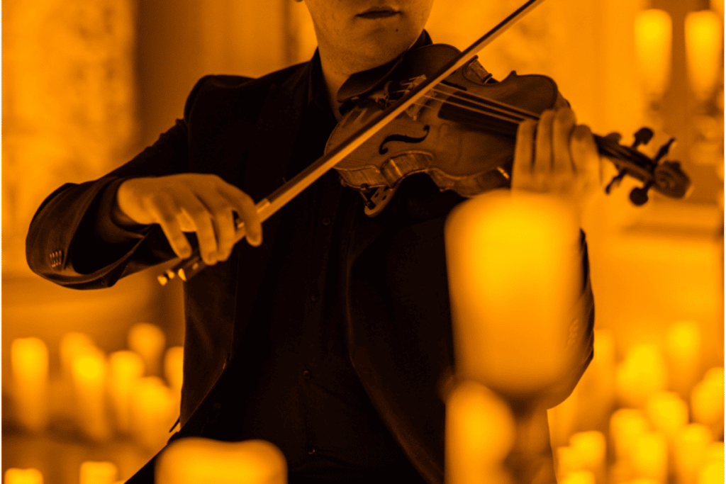 Man playing the violin surrounded by candles