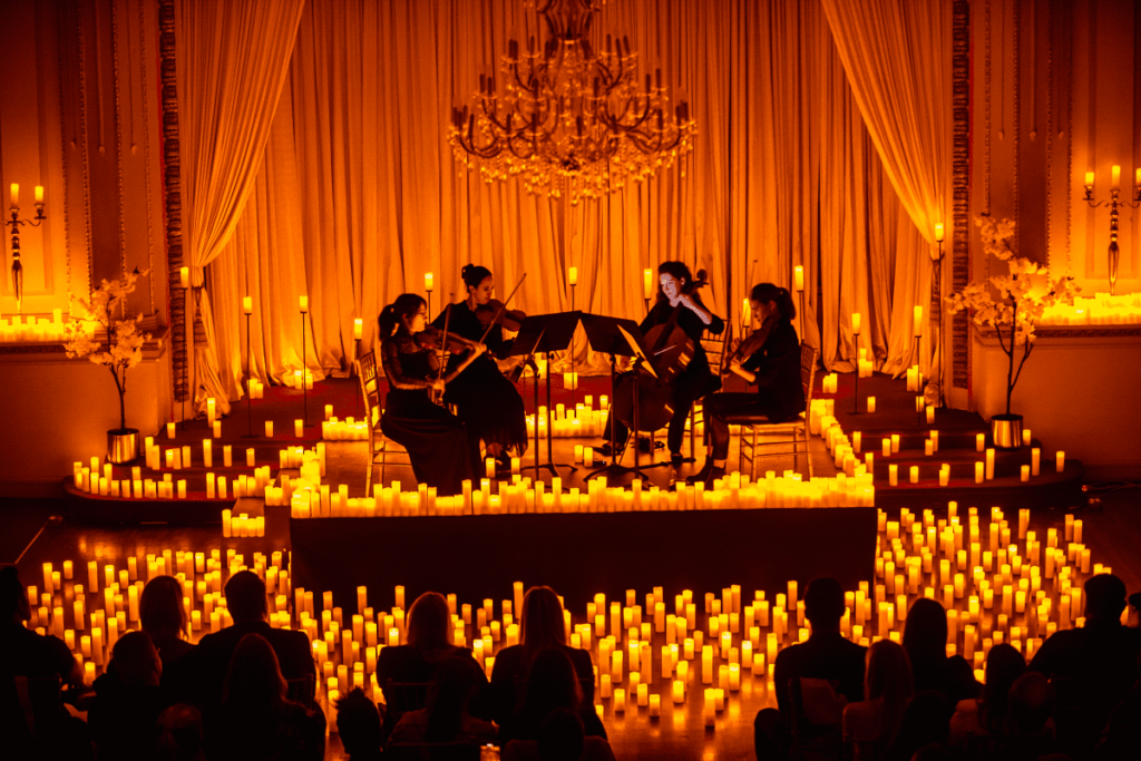 A string quartet performing on stage surrounded by candles